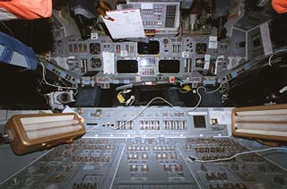 Views of the control boards in the Atlantis forward flight deck, including light fixtures and the pilot and commander's station seats. 